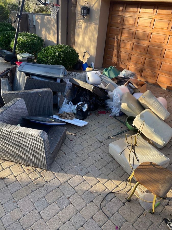 Patio furniture, cushions and household items on a driveway