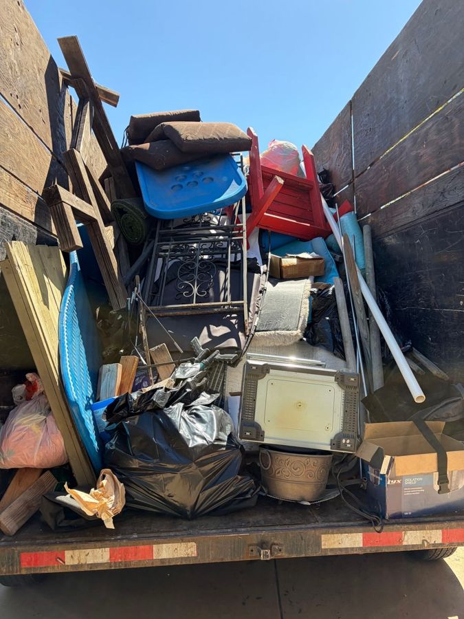 Trailer loaded with patio furniture, wood and yard items